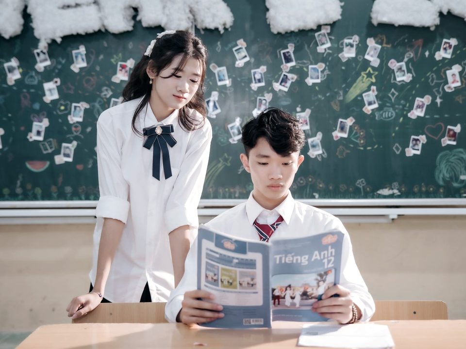 Chị học sinh lớn kèm em đọc sách Tiếng Anh